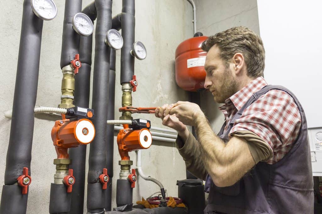 plumber working on heater pipes underground